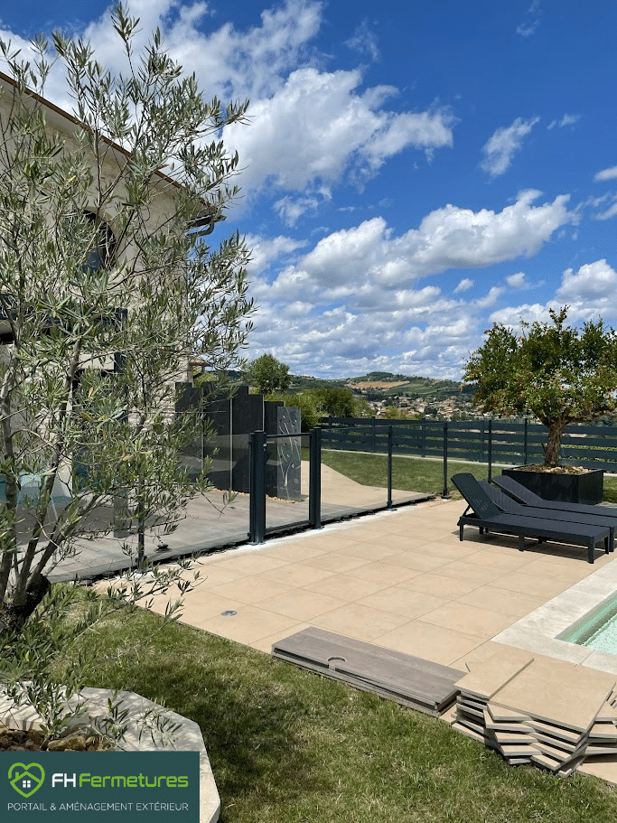 Barrière piscine en verre avec portillon aluminium installée autour d'une piscine creusée à Villefranche-sur-Saône (69) par FH Fermetures