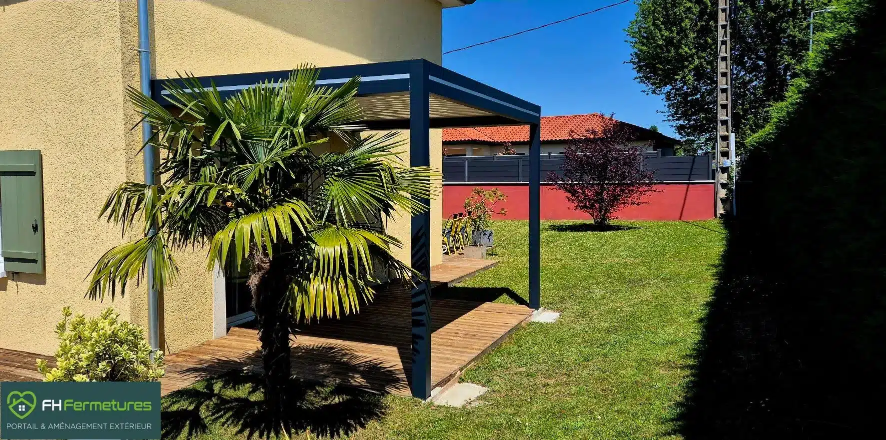 Pergola bioclimatique aluminium anthracite adossée à la façade sur deux poteaux installée sur terrasse bois à Chessy (69) par FH Fermetures