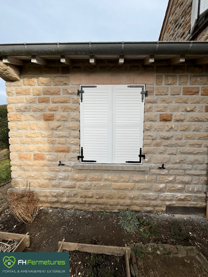 Volets battants faux persienne aluminium blanc avec ferrages noirs installés sur maison en pierre à Mâcon (71) par FH Fermetures