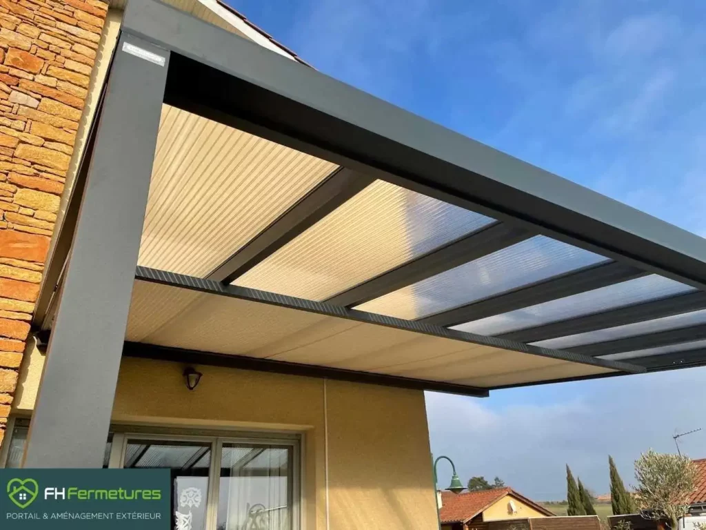 Auvent alu sur-mesure avec toiture polycarbonate clair et store motorisé installé à Belleville (69) par FH Fermetures