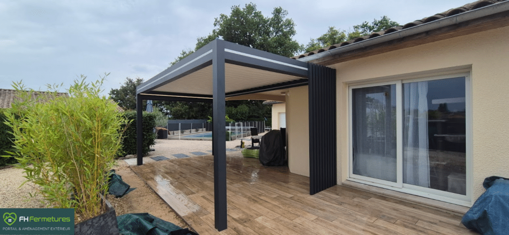 Pergola bioclimatique aluminium anthracite avec boucliers et éclairage LED installée sur terrasse bois à Crottet (01) par FH Fermetures